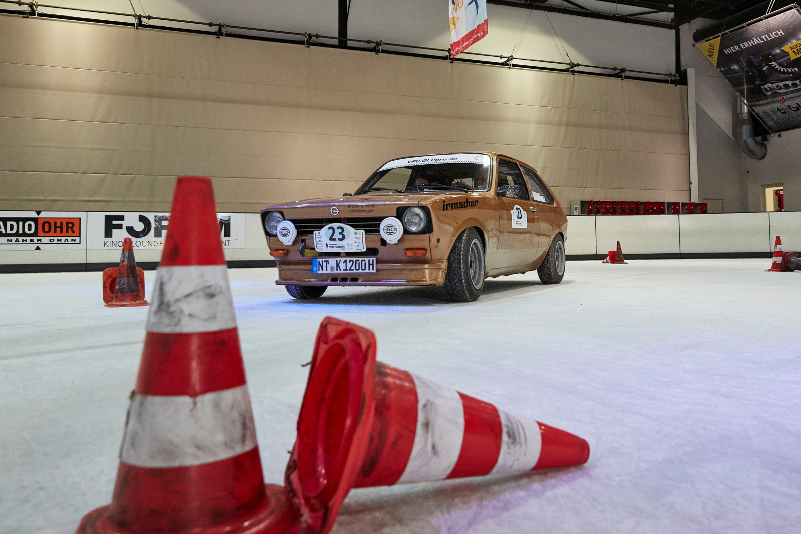 Ein goldenes Auto mit der Nummer 23 auf Eis, im Vordergrund zwei Leitkegel